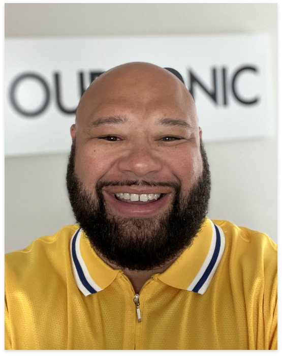 Meo, founder of Ourconic, smiling in a yellow polo shirt with the Ourconic logo in the background